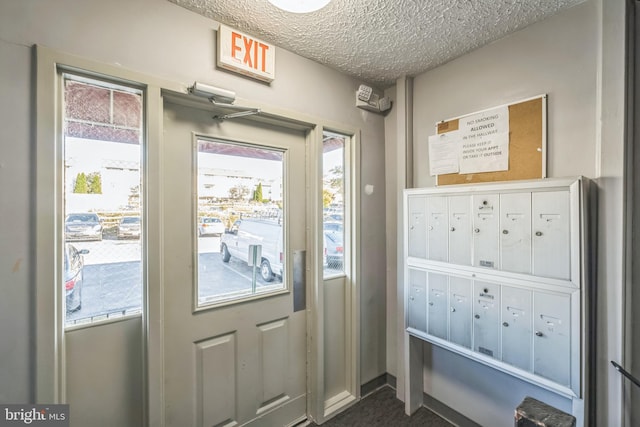 doorway to outside featuring a textured ceiling and mail boxes