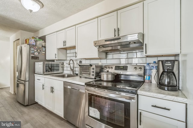 kitchen with sink, appliances with stainless steel finishes, light hardwood / wood-style flooring, and white cabinetry