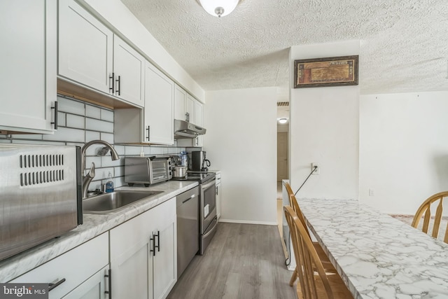 kitchen featuring sink, white cabinetry, a textured ceiling, and light wood-type flooring