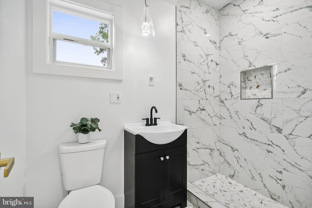 bathroom with toilet, vanity, and tiled shower