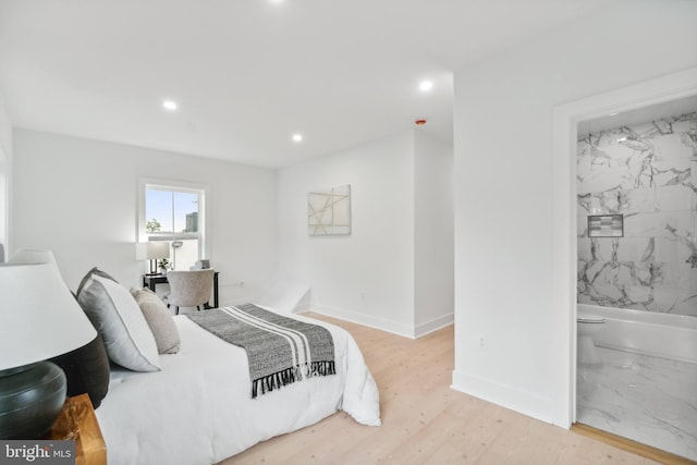 bedroom with connected bathroom and light hardwood / wood-style flooring