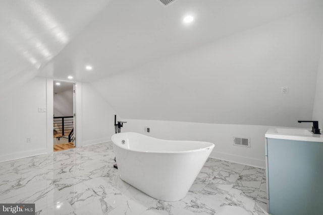 bathroom with a washtub, lofted ceiling, and vanity