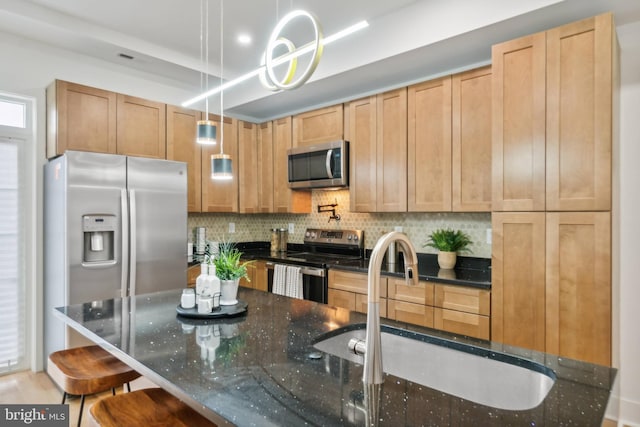 kitchen with pendant lighting, dark stone countertops, stainless steel appliances, and a breakfast bar area