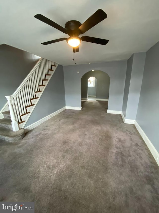 unfurnished living room with ceiling fan and dark colored carpet