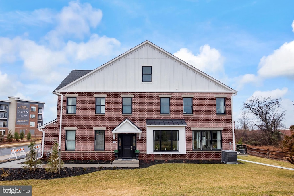 view of front of home with central AC unit, a front yard, brick siding, and board and batten siding