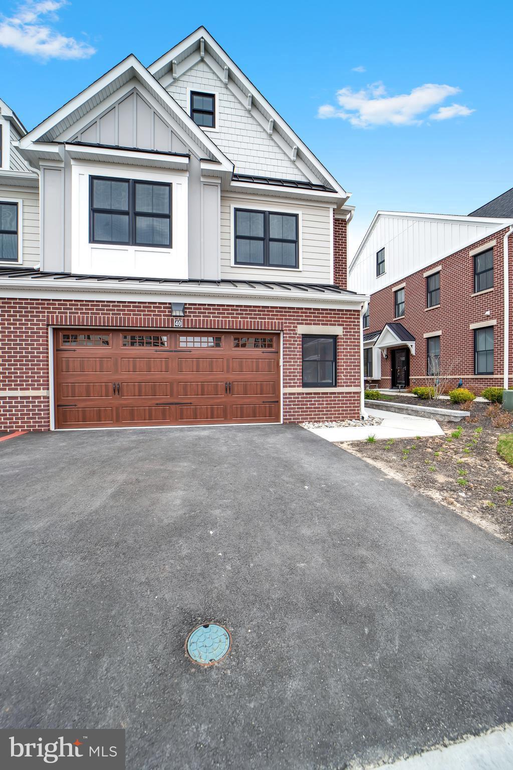 view of front of property with aphalt driveway, an attached garage, board and batten siding, and brick siding