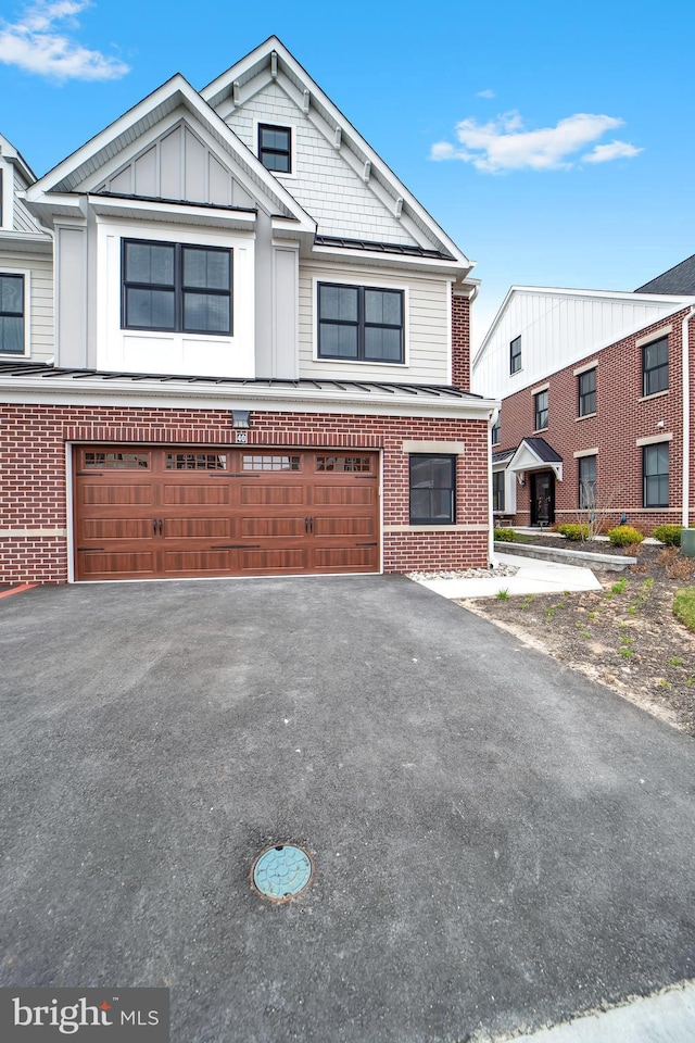view of front of property with aphalt driveway, an attached garage, board and batten siding, and brick siding