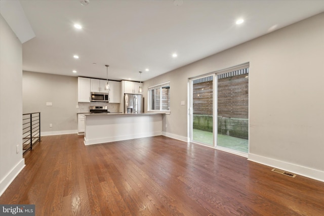 unfurnished living room featuring dark hardwood / wood-style flooring and a wealth of natural light