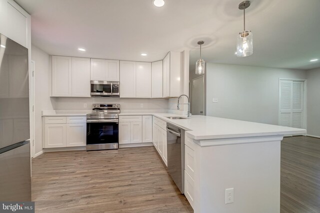 kitchen with kitchen peninsula, white cabinets, stainless steel appliances, and sink