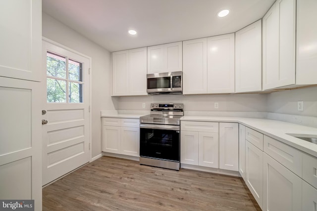 kitchen featuring appliances with stainless steel finishes, white cabinets, and light wood-type flooring