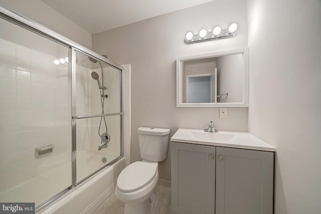 full bathroom featuring vanity, toilet, combined bath / shower with glass door, and tile patterned flooring