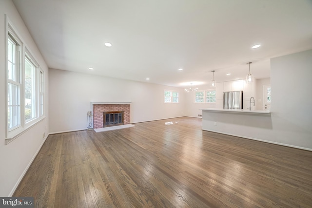 unfurnished living room featuring dark hardwood / wood-style floors, sink, and a fireplace