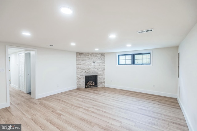 unfurnished living room with a stone fireplace and light wood-type flooring