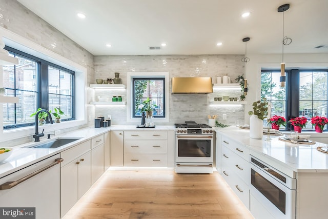 kitchen featuring premium range hood, white cabinets, gas range oven, and decorative light fixtures