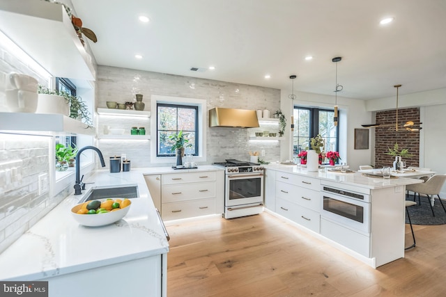 kitchen with sink, decorative light fixtures, light wood-type flooring, high end white range, and white cabinets