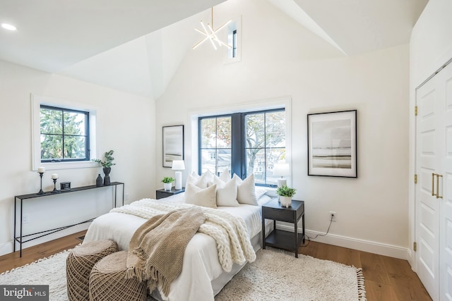 bedroom featuring wood-type flooring, lofted ceiling, and a chandelier