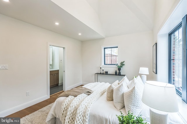 bedroom with hardwood / wood-style flooring, vaulted ceiling, and connected bathroom