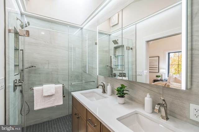 bathroom featuring vanity, a shower with shower door, and decorative backsplash