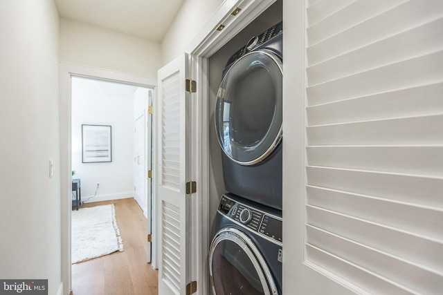 clothes washing area with stacked washing maching and dryer and light hardwood / wood-style flooring