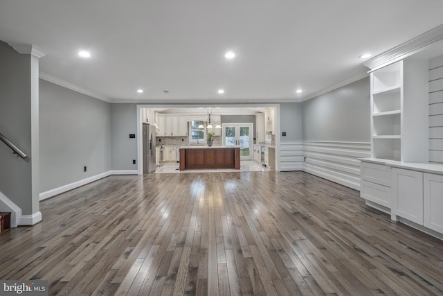 unfurnished living room with wood-type flooring, an inviting chandelier, and ornamental molding