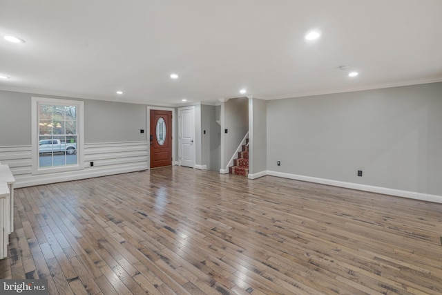 unfurnished living room featuring ornamental molding and light wood-type flooring