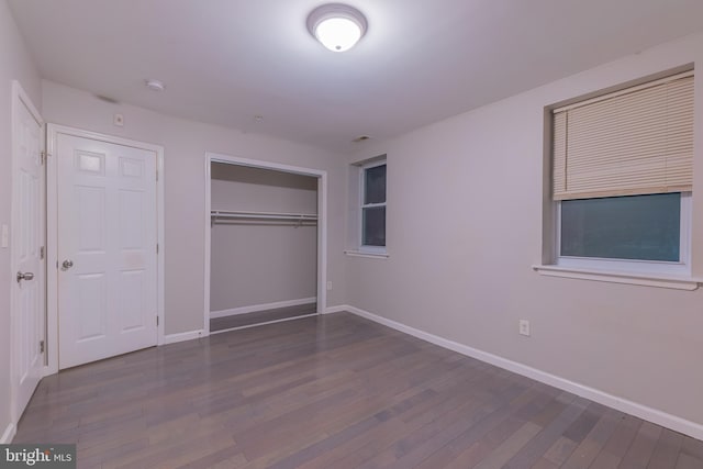 unfurnished bedroom with a closet and dark hardwood / wood-style floors