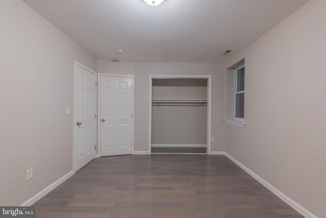 unfurnished bedroom featuring a closet and dark wood-type flooring