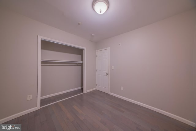 unfurnished bedroom with a closet and dark hardwood / wood-style floors