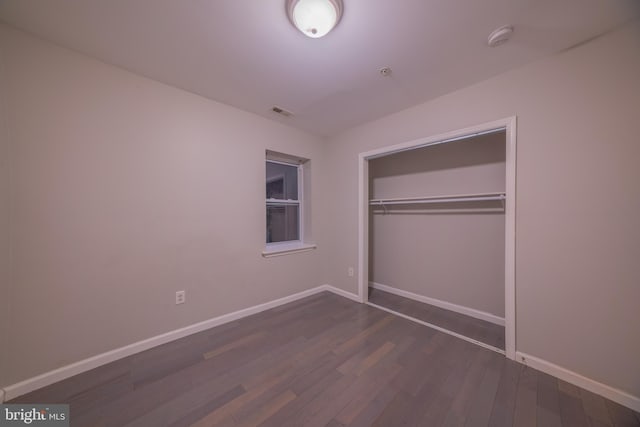 unfurnished bedroom with a closet and dark hardwood / wood-style floors