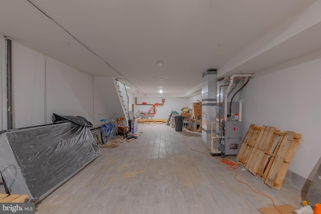 basement featuring light wood-type flooring and heating unit