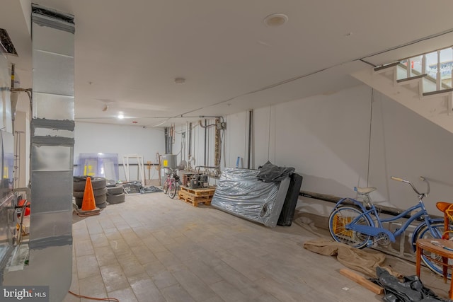 basement featuring light wood-type flooring and water heater