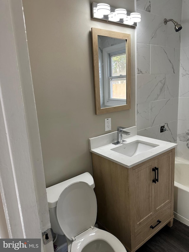 full bathroom with vanity, tiled shower / bath combo, hardwood / wood-style flooring, and toilet