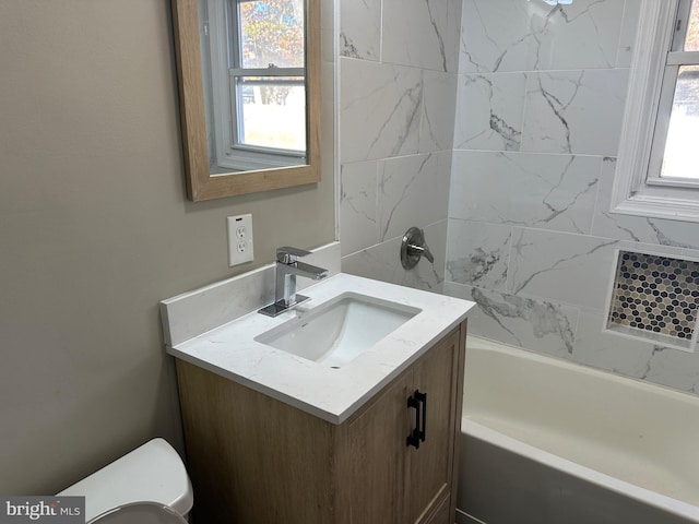 bathroom with vanity, a tub to relax in, toilet, and a wealth of natural light