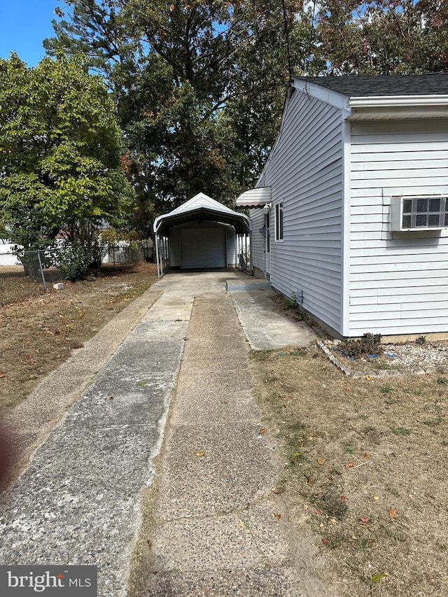 view of property exterior featuring concrete driveway, a detached carport, and a wall mounted air conditioner