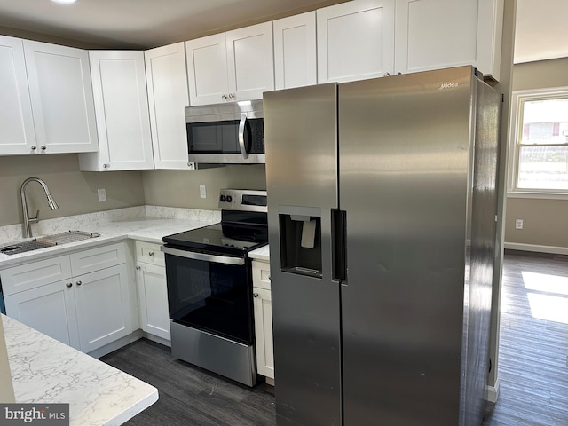 kitchen with light stone counters, dark hardwood / wood-style flooring, white cabinetry, sink, and stainless steel appliances