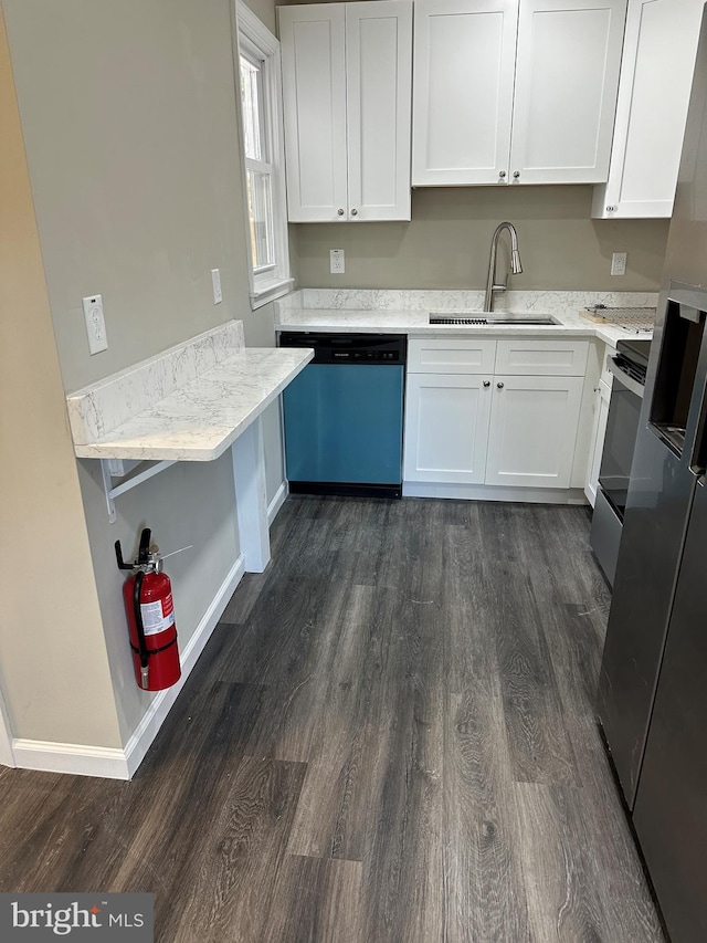 kitchen with sink, white cabinets, appliances with stainless steel finishes, light stone counters, and dark hardwood / wood-style flooring