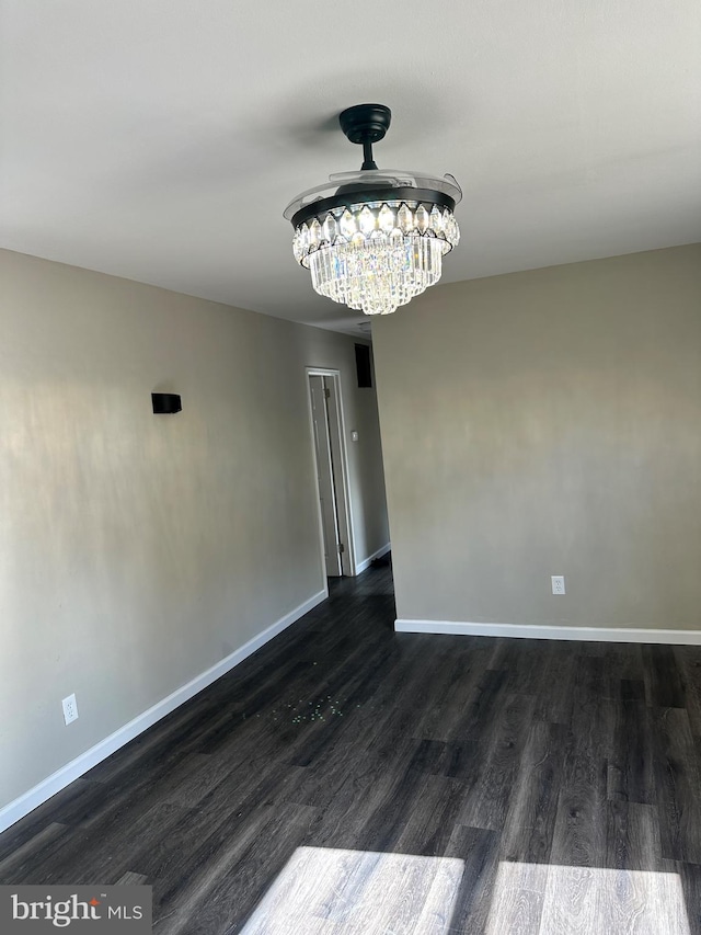 spare room with a notable chandelier and dark hardwood / wood-style flooring