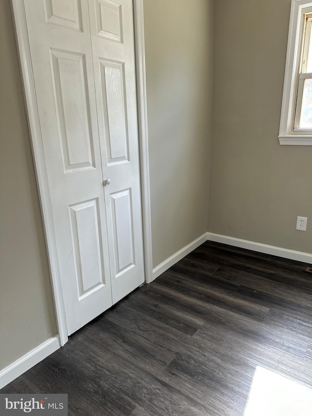 unfurnished bedroom featuring dark wood-style flooring and baseboards