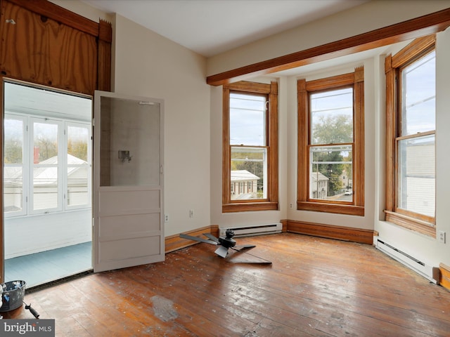 unfurnished room featuring baseboard heating, light wood-type flooring, and a healthy amount of sunlight