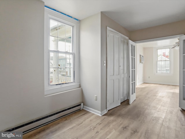 hallway with light hardwood / wood-style flooring, a wall mounted AC, and a baseboard radiator