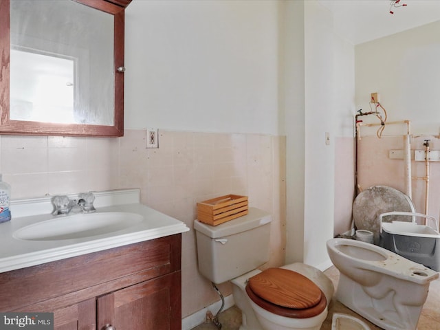 bathroom featuring toilet, vanity, and tile walls