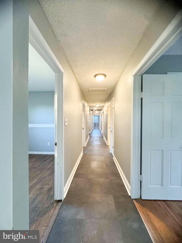 hall with a textured ceiling and dark hardwood / wood-style flooring