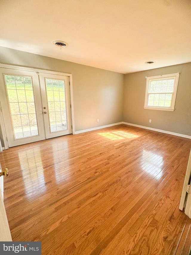 unfurnished room featuring french doors, plenty of natural light, and light wood-type flooring