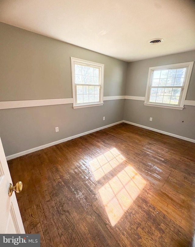 spare room featuring a wealth of natural light and dark hardwood / wood-style floors