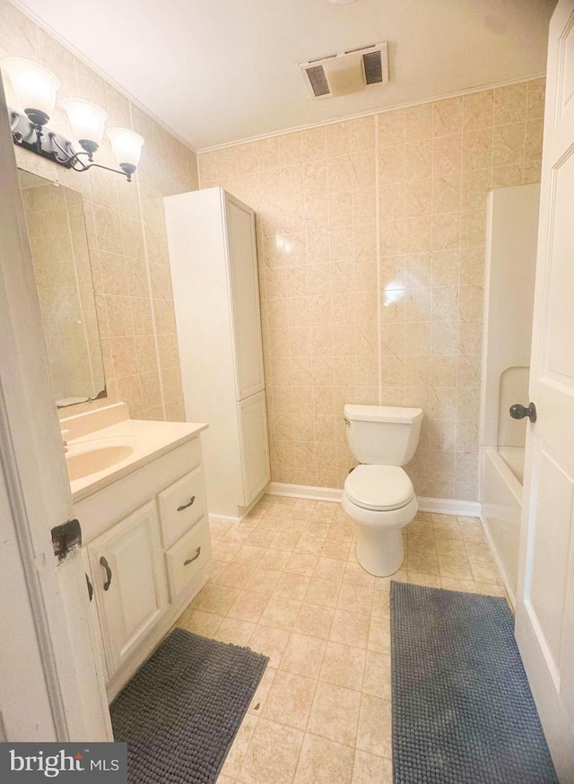 full bathroom with vanity, toilet, and tile walls