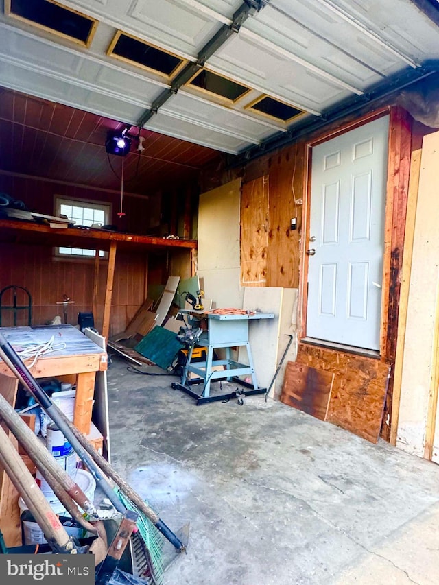 garage featuring a workshop area, wood walls, and a garage door opener