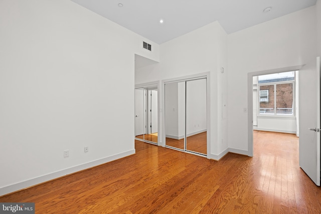 unfurnished bedroom featuring a towering ceiling and light wood-type flooring