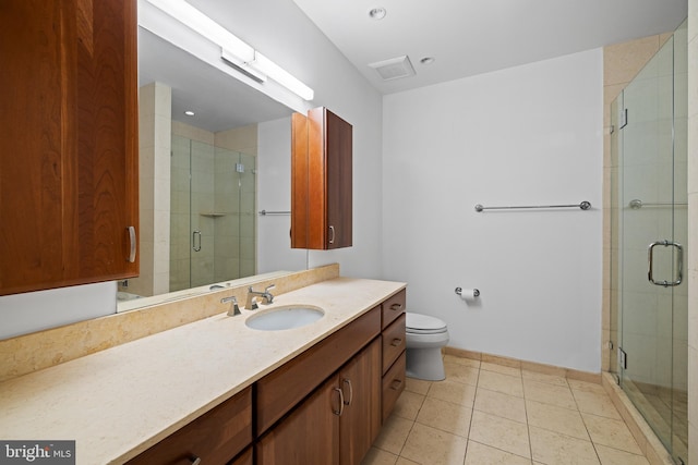 bathroom with vanity, toilet, tile patterned floors, and a shower with door