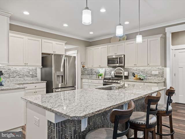 kitchen featuring white cabinetry, decorative backsplash, a kitchen island with sink, and stainless steel appliances