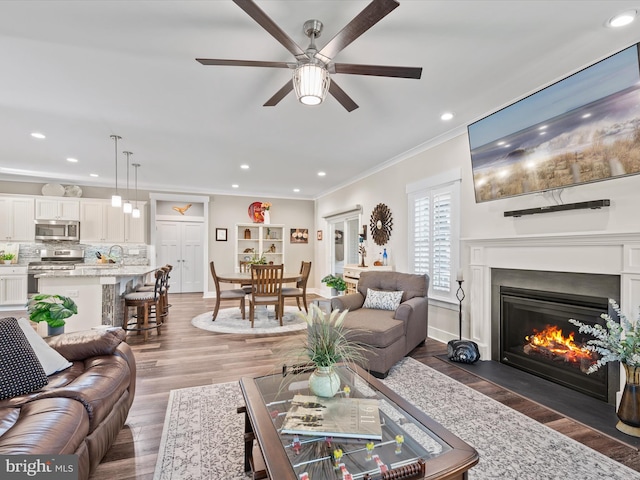 living room with dark hardwood / wood-style floors, ceiling fan, and crown molding